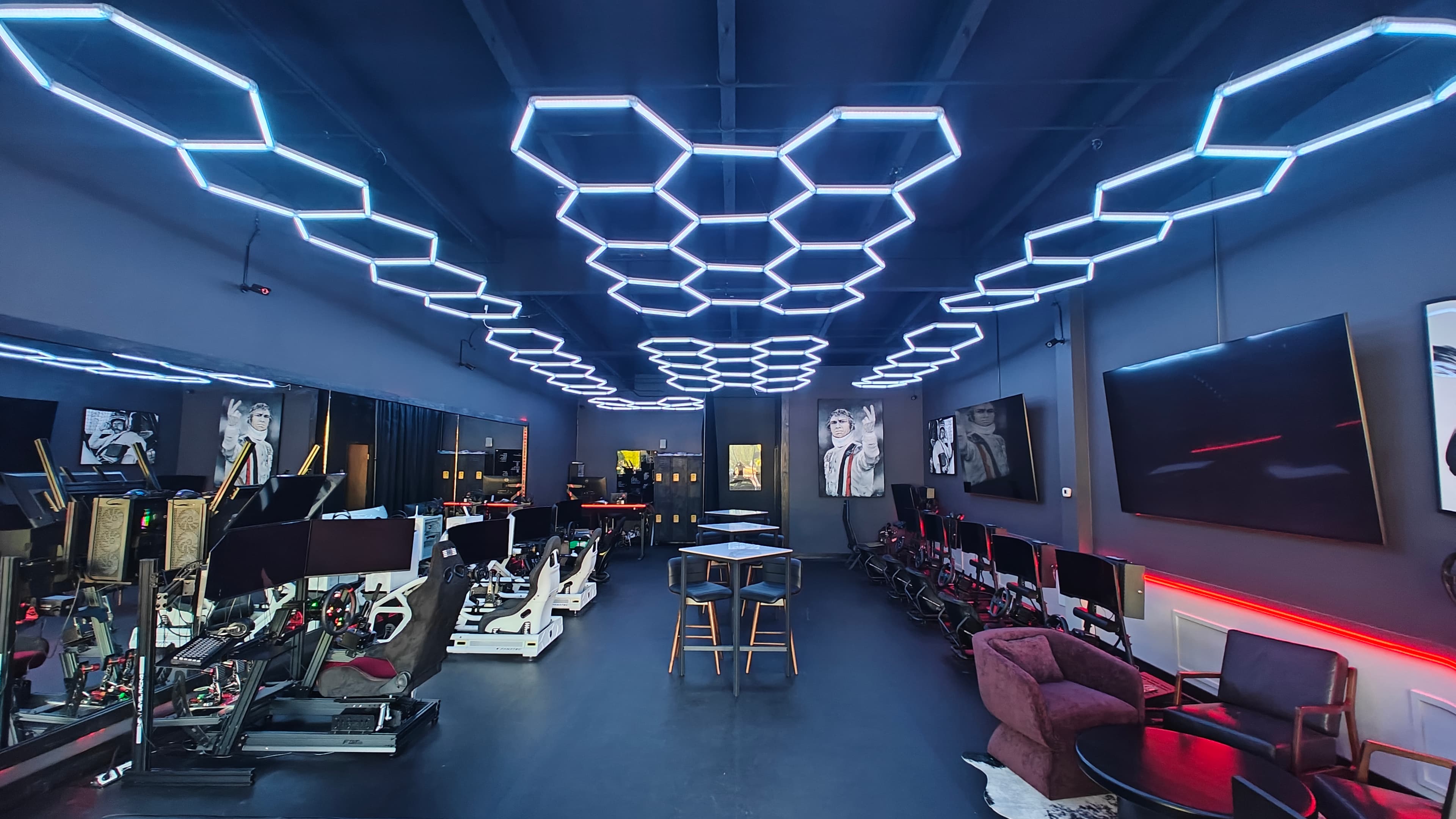 Interior of Kartcade — rows of sim racing cockpits beneath a hexagonal LED ceiling array